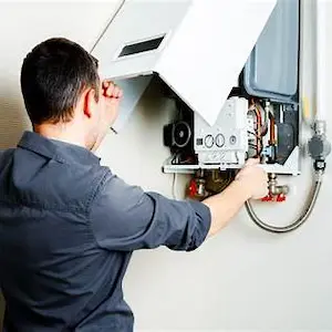 «تعمیرکار در حال بررسی و تعمیر پکیج دیواری برای رفع مشکل گرمایش»